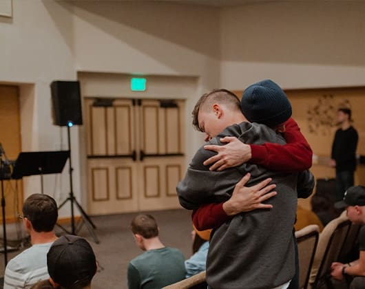 Two participants embrace during a Good Landing Recovery church service in Georgia