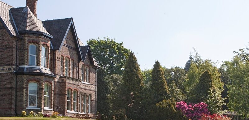 Victorian exterior of Priory Hospital Altrincham among landscaped lawns and mature trees