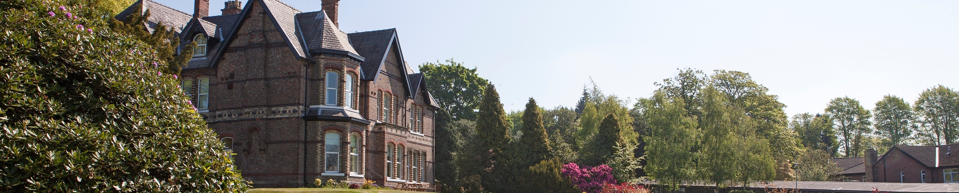 Victorian exterior of Priory Hospital Altrincham among landscaped lawns and mature trees