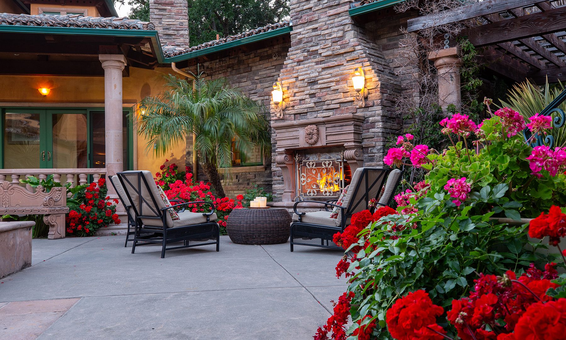 Reflections outdoor courtyard with a stone fireplace, lounge chairs and flowering plants