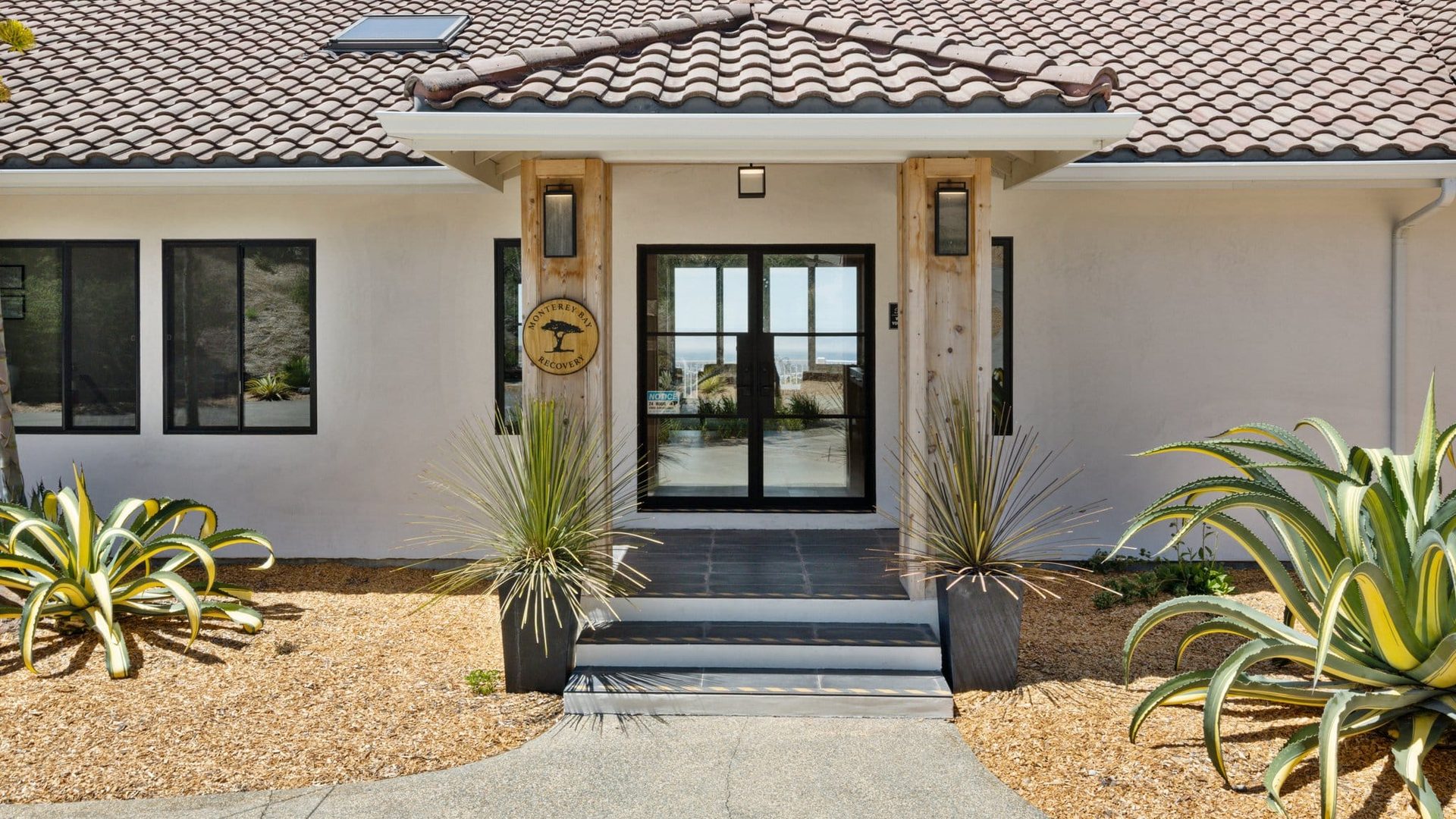Front entrance at Monterey Bay Recovery with its wooden center sign and planted grounds